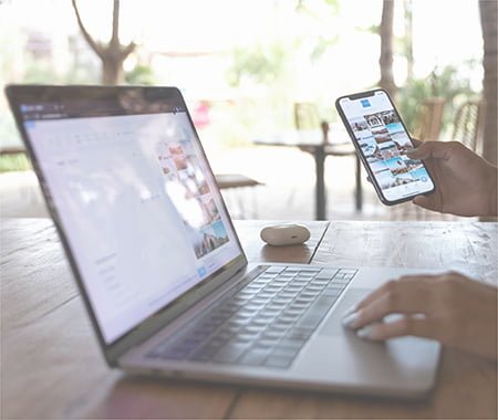 A woman is checking something on her laptop and holding a mobile phone